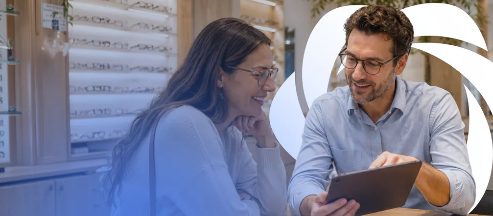 A smiling customer and an optician going through options on a tablet in an optical store.